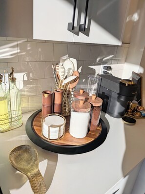 A kitchen counter with various utensils, a coffee maker, and a glass container.