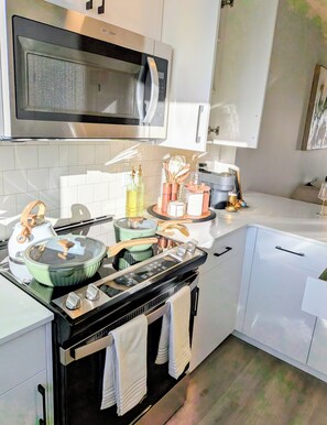 A modern kitchen with a built-in microwave, stove, and oven. There are various kitchen utensils and appliances on the counter.