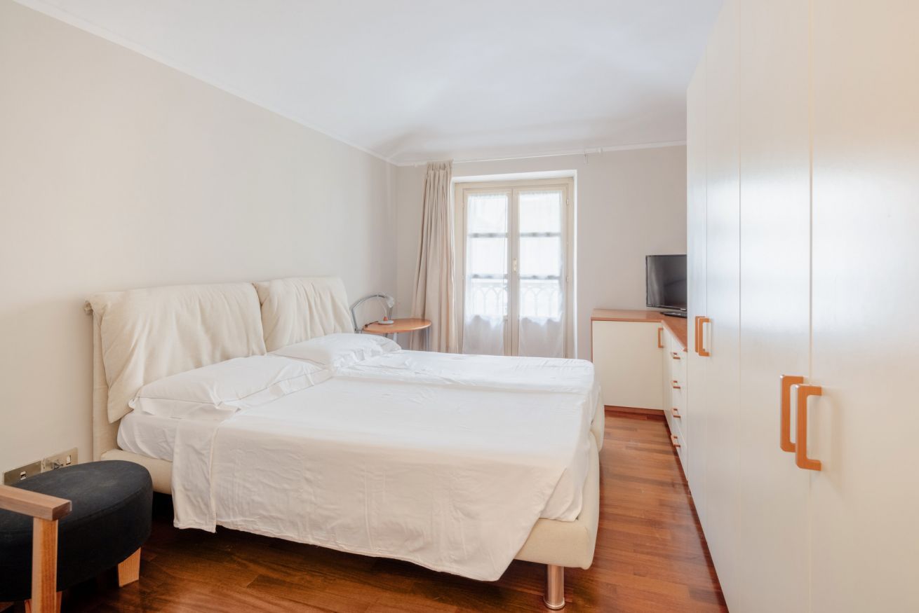 Ein Schlafzimmer mit Doppelbett, Nachttisch, Fernseher und Kleiderschrank.