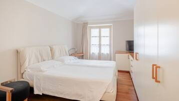 Ein Schlafzimmer mit Doppelbett, Nachttisch, Fernseher und Kleiderschrank.