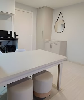 A modern kitchen with white cabinetry, a white countertop, and a hanging mirror.