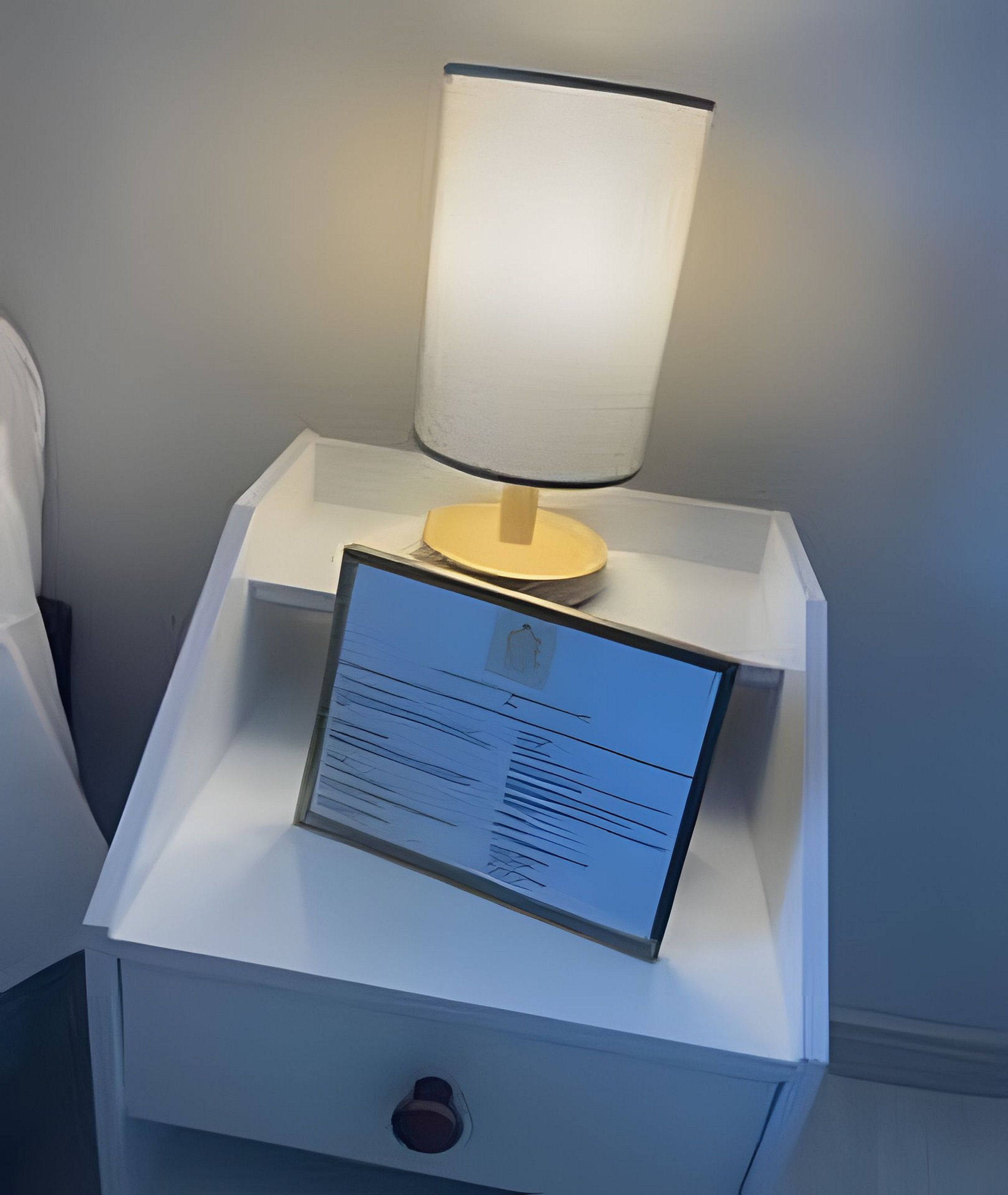 A bedside table with a lamp and a sign.