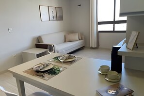 Una sala de estar moderna con un sofá, una mesa de comedor para dos personas y una pequeña mesa de centro.