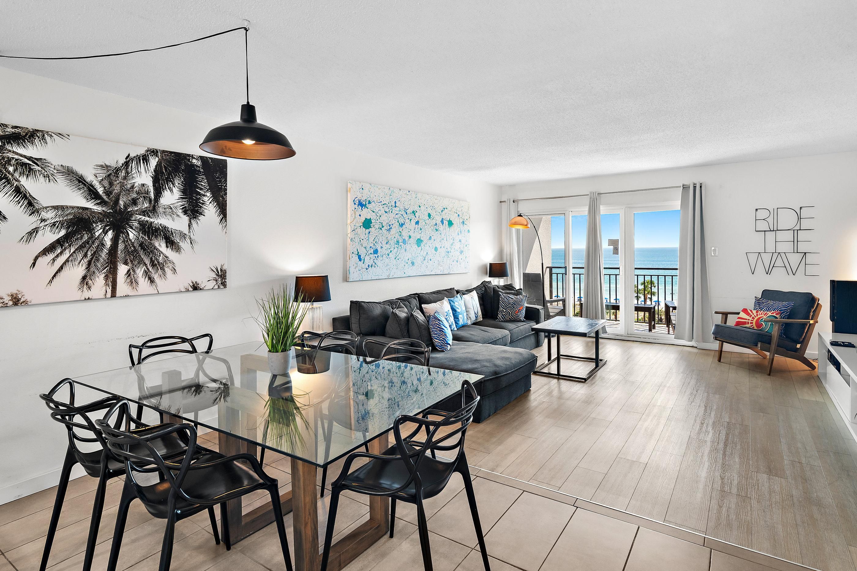 A modern living space with a dining area, a sofa set, and a view of the ocean.