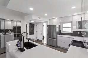 A modern kitchen with a central island, stainless steel appliances, and a minimalist design. - Emerald Isle 612 (Fort Walton Beach)