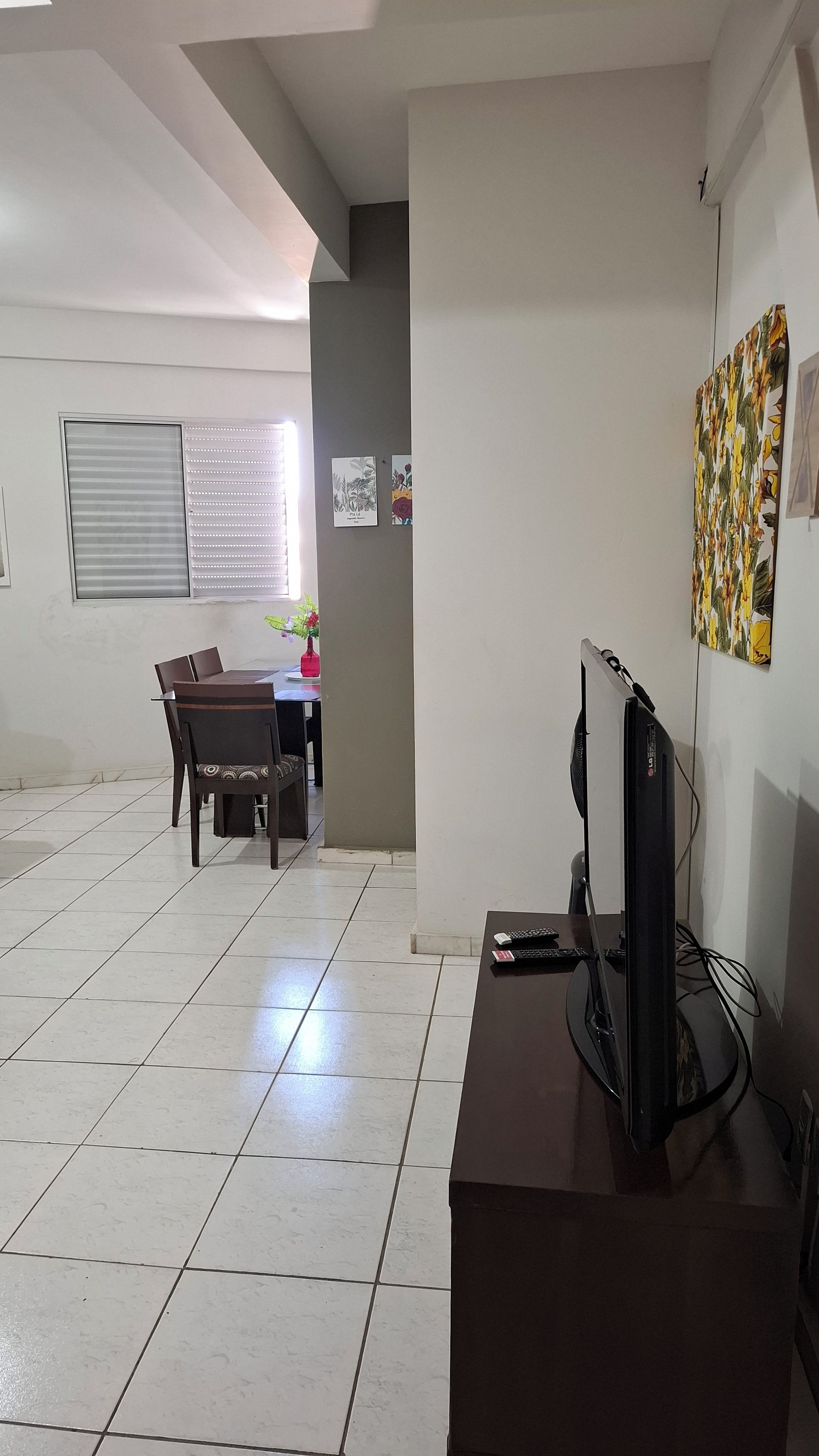 Ein Zimmer mit Esstisch, Stühlen, Fernseher und Bildern an der Wand.