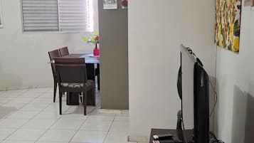 Ein Zimmer mit Esstisch, Stühlen, Fernseher und Bildern an der Wand.