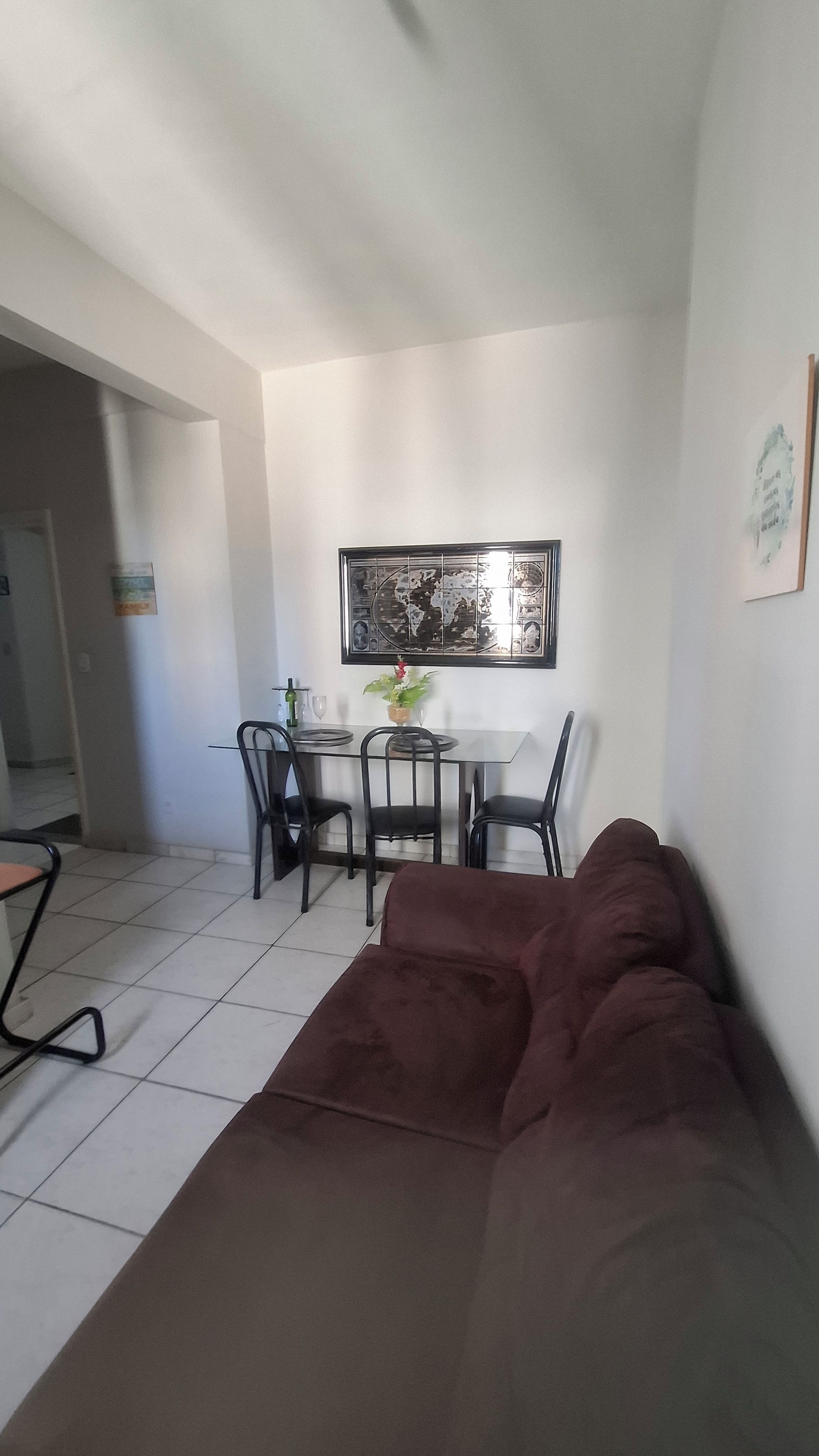 Un salon avec un canapé marron, une table à manger avec des chaises et une grande œuvre d’art encadrée accrochée au mur.