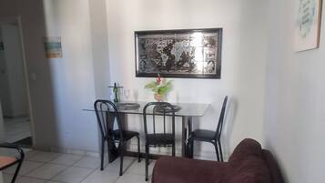 Un salon avec un canapé marron, une table à manger avec des chaises et une grande œuvre d’art encadrée accrochée au mur.