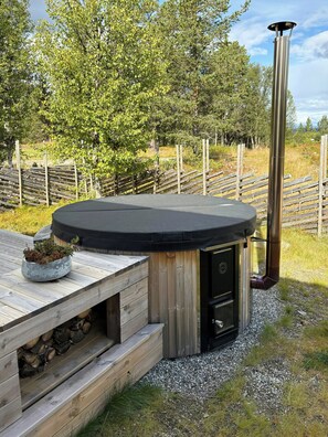 A hot tub with a wooden deck, a metal chimney, and a surrounding fence. - Mountain cabin in Peer Gynt country, ski-in/out (Sør-Fron)