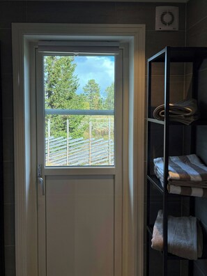 A door with a window, a towel rack with towels, and a wall-mounted air conditioning unit. - Mountain cabin in Peer Gynt country, ski-in/out (Sør-Fron)