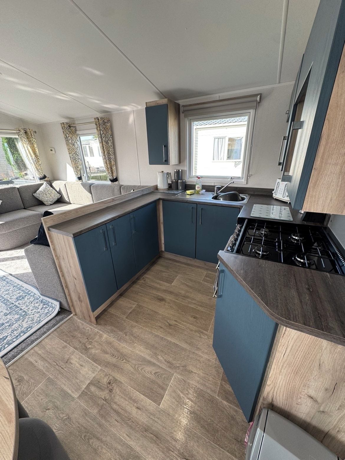 A compact kitchen with a built-in stove, dark blue cabinets, and a window providing natural light.