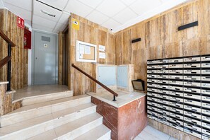 A staircase with a handrail leading to a door, a wall-mounted fire extinguisher, and a bulletin board with notices. - MalagaSuite Urban Beach B (Torremolinos)
