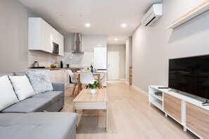 A modern living room with a grey sofa, a coffee table, and a TV on a wooden stand. - MalagaSuite Urban Beach B (Torremolinos)