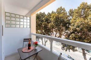 A balcony with a table, a bottle, and a flower. - MalagaSuite Urban Beach B (Torremolinos)
