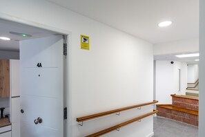 A hallway with a white door labeled '4A', a yellow safety sign, and a wooden handrail. - MalagaSuite Urban Beach B (Torremolinos)