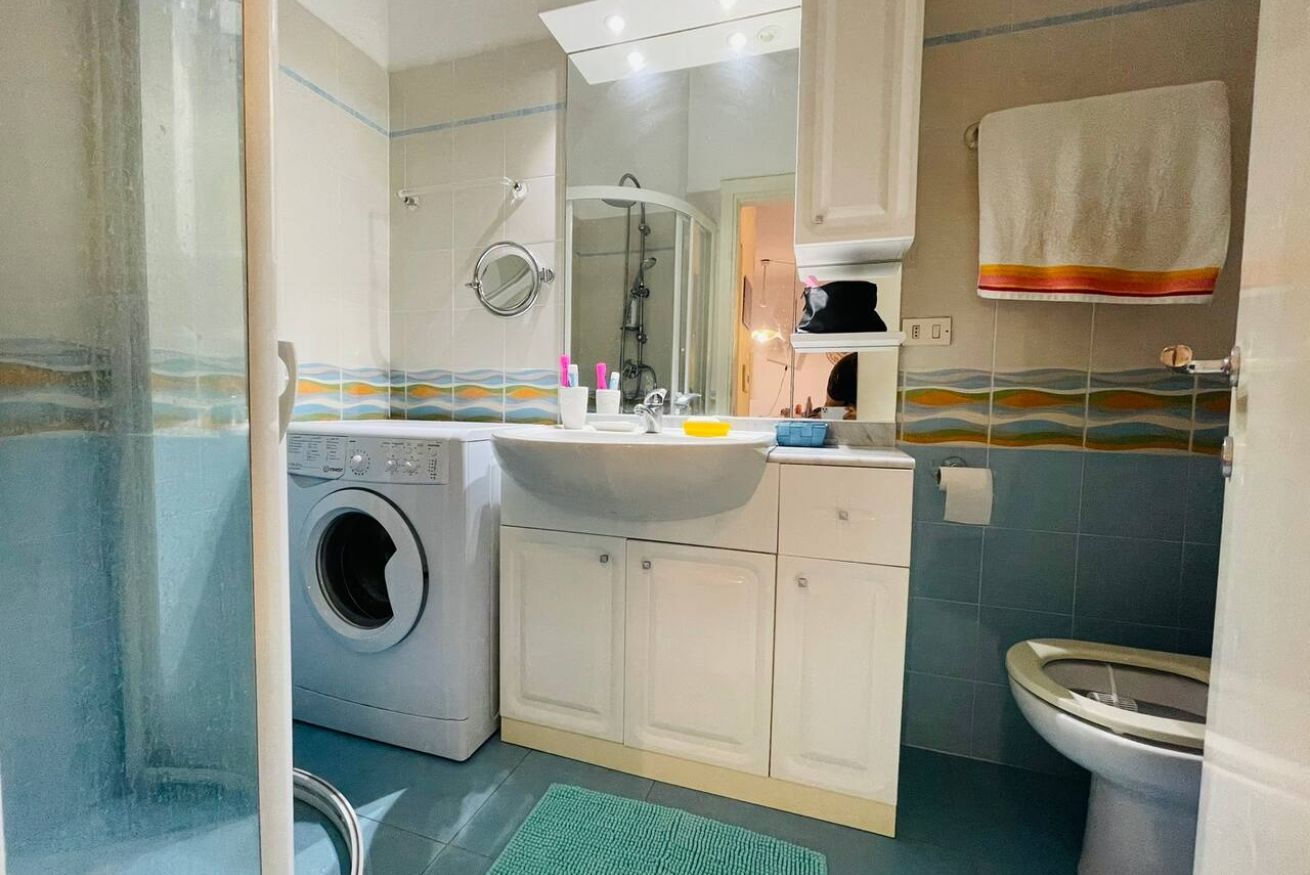 Une petite salle de bain équipée d’un lave-linge, d’un évier et de toilettes.