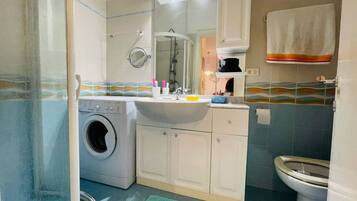 Ein kleines Badezimmer mit Waschmaschine, Waschbecken und Toilette.