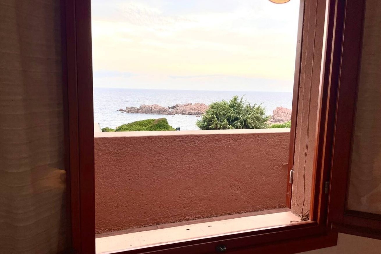 Ein Fenster mit Blick auf das Meer und Felsformationen.