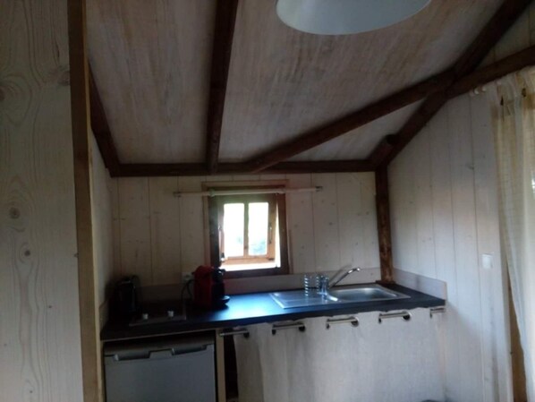 Una piccola cucina con lavello, finestra e pareti in legno.