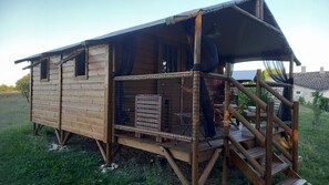 Una baita di legno con un portico coperto e un'area recintata.