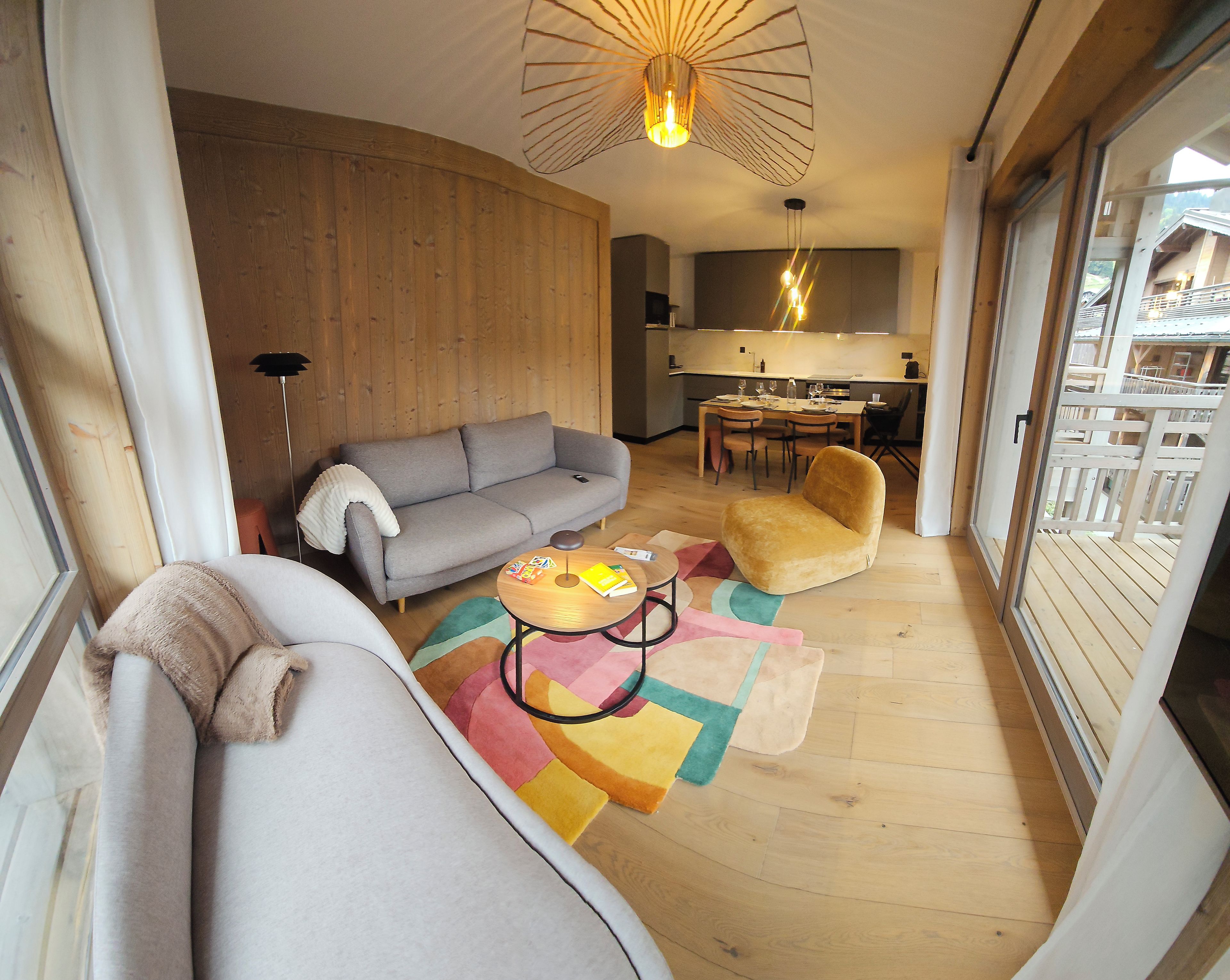A living room with a sofa, armchair, and coffee table, a dining area with chairs, and a kitchen in the background.