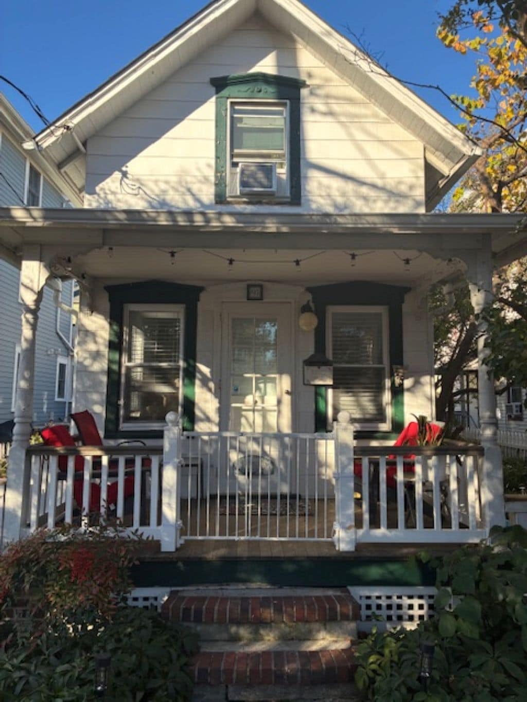 A two-story house with a porch, a front door, and a small window above the door.