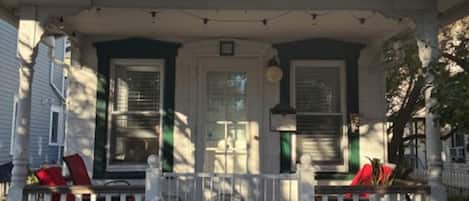 A two-story house with a porch, a front door, and a small window above the door.