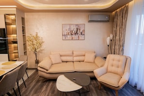 Uma sala de estar moderna com um sofá seccional, uma mesa de centro redonda e uma área de jantar com mesa e cadeiras.