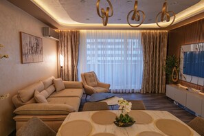 A modern living room with a sectional sofa, a coffee table, and a TV. - Designer Luxery 2 BR Apartment with Hot Mineral Water & Mineral Pool (VARNA)