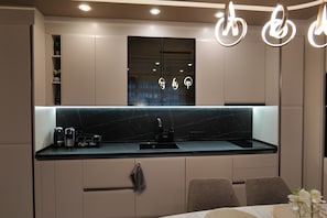 A modern kitchen with a black countertop, a coffee machine, and a sink. - Designer Luxery 2 BR Apartment with Hot Mineral Water & Mineral Pool (VARNA)