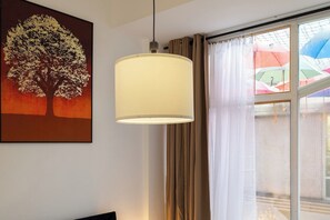 A room with a large window, a hanging lamp, and a painting of a tree. - Central Brighton 2BR | Sleeps 4 | Near Seafront (Brighton and Hove)