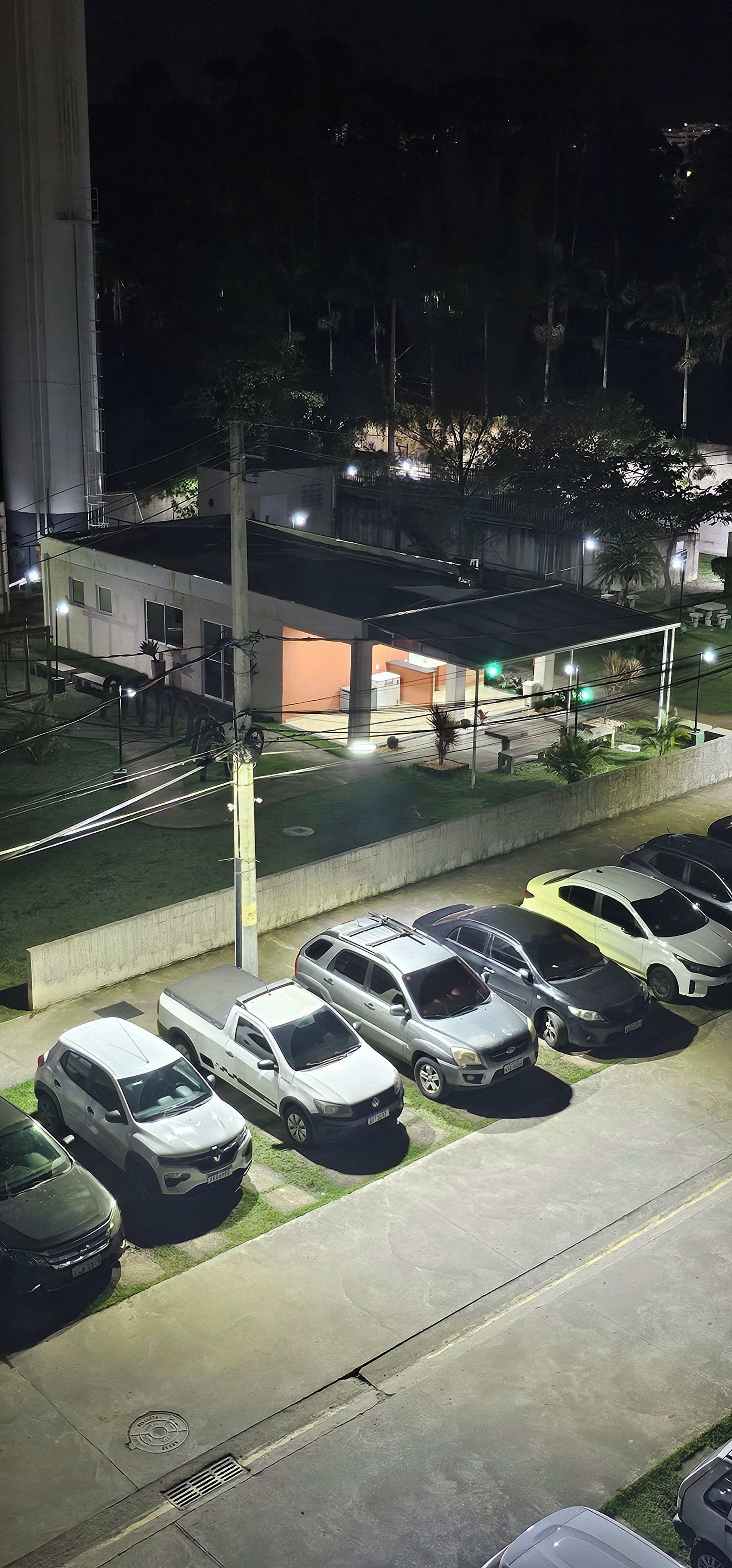 A parking lot with several cars, a building with a flat roof, and a green traffic light.