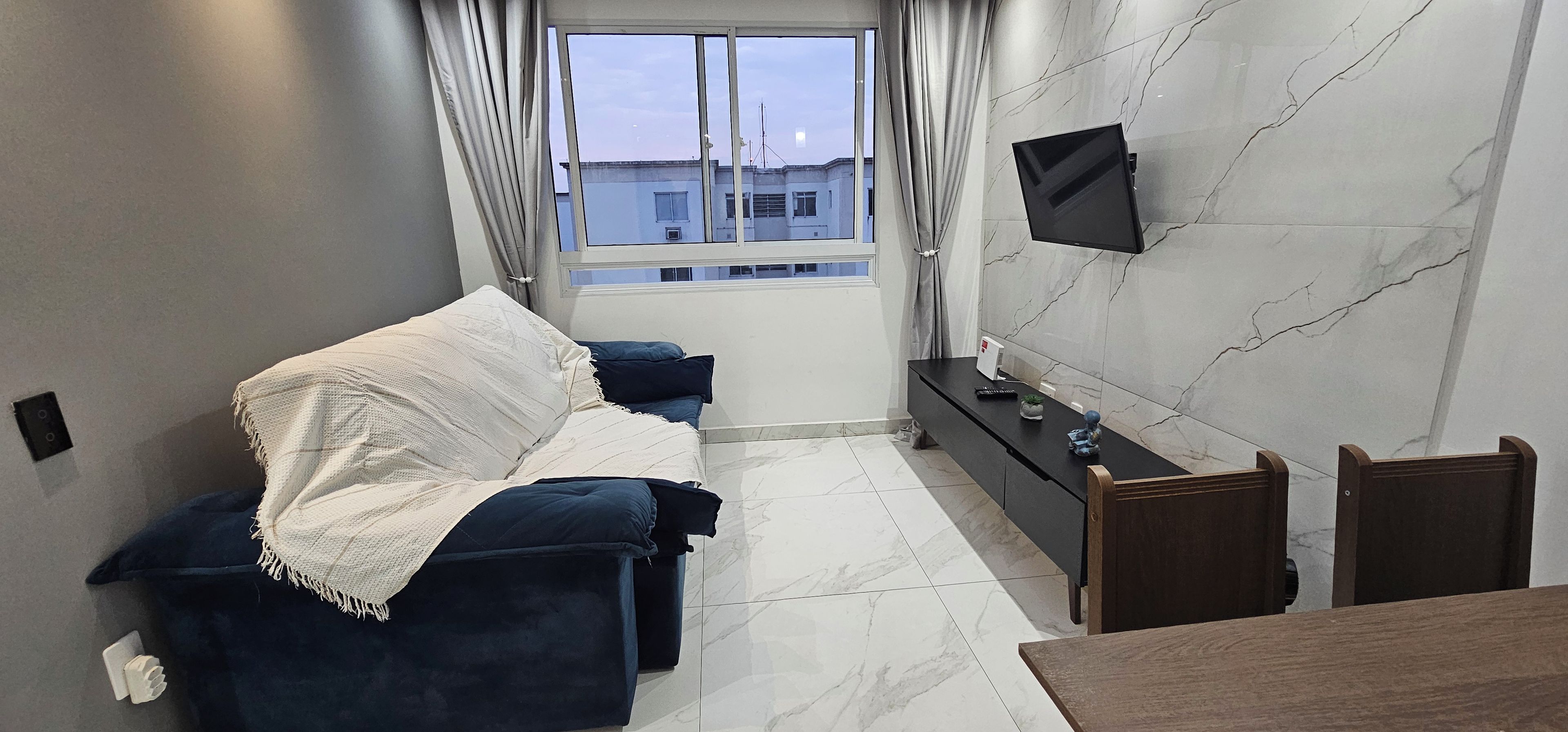 A modern living room with a sofa, TV, and a small table.