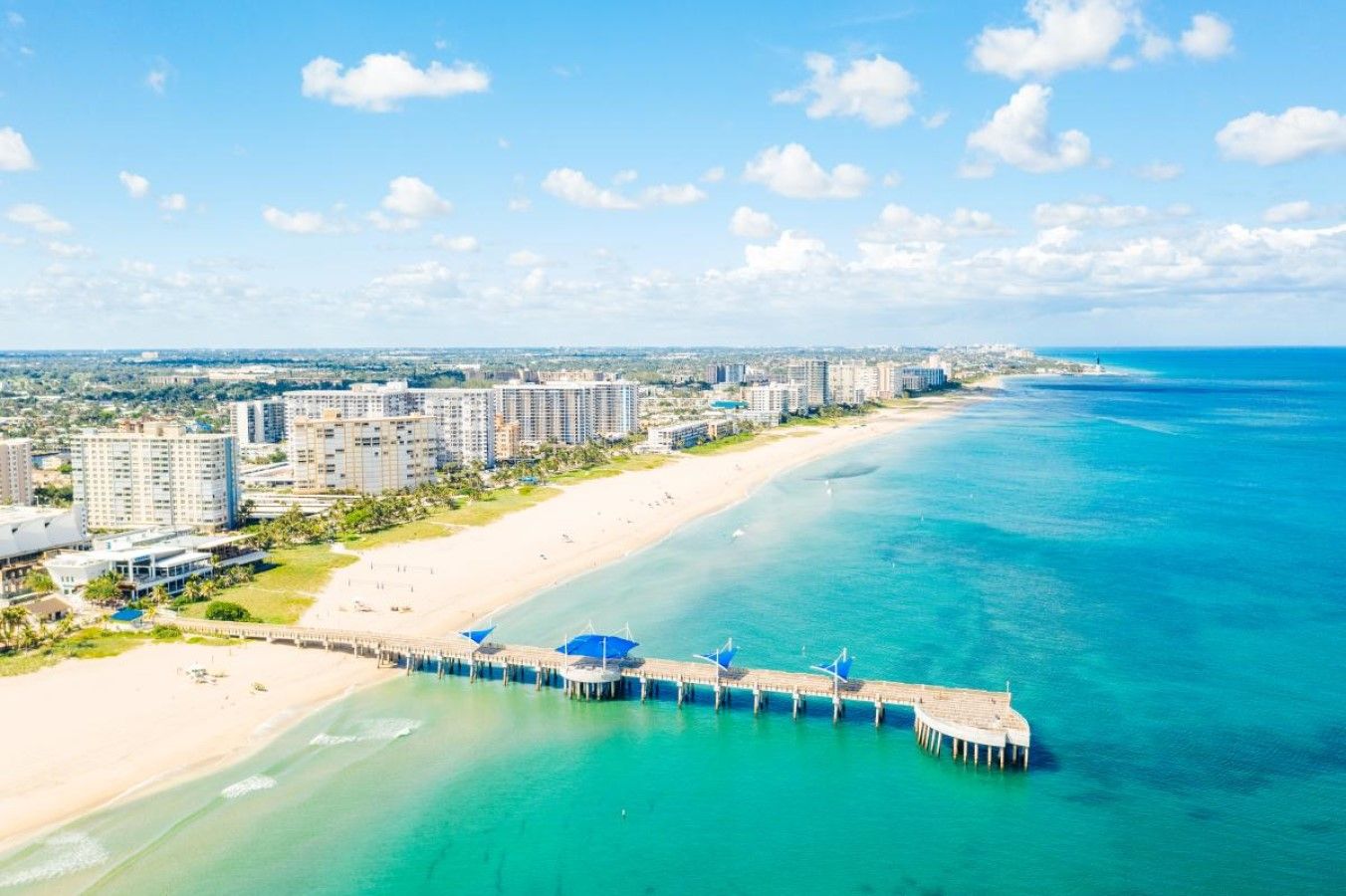 Une zone hôtelière située sur la côte, avec une plage, une jetée et des immeubles de grande hauteur en arrière-plan.