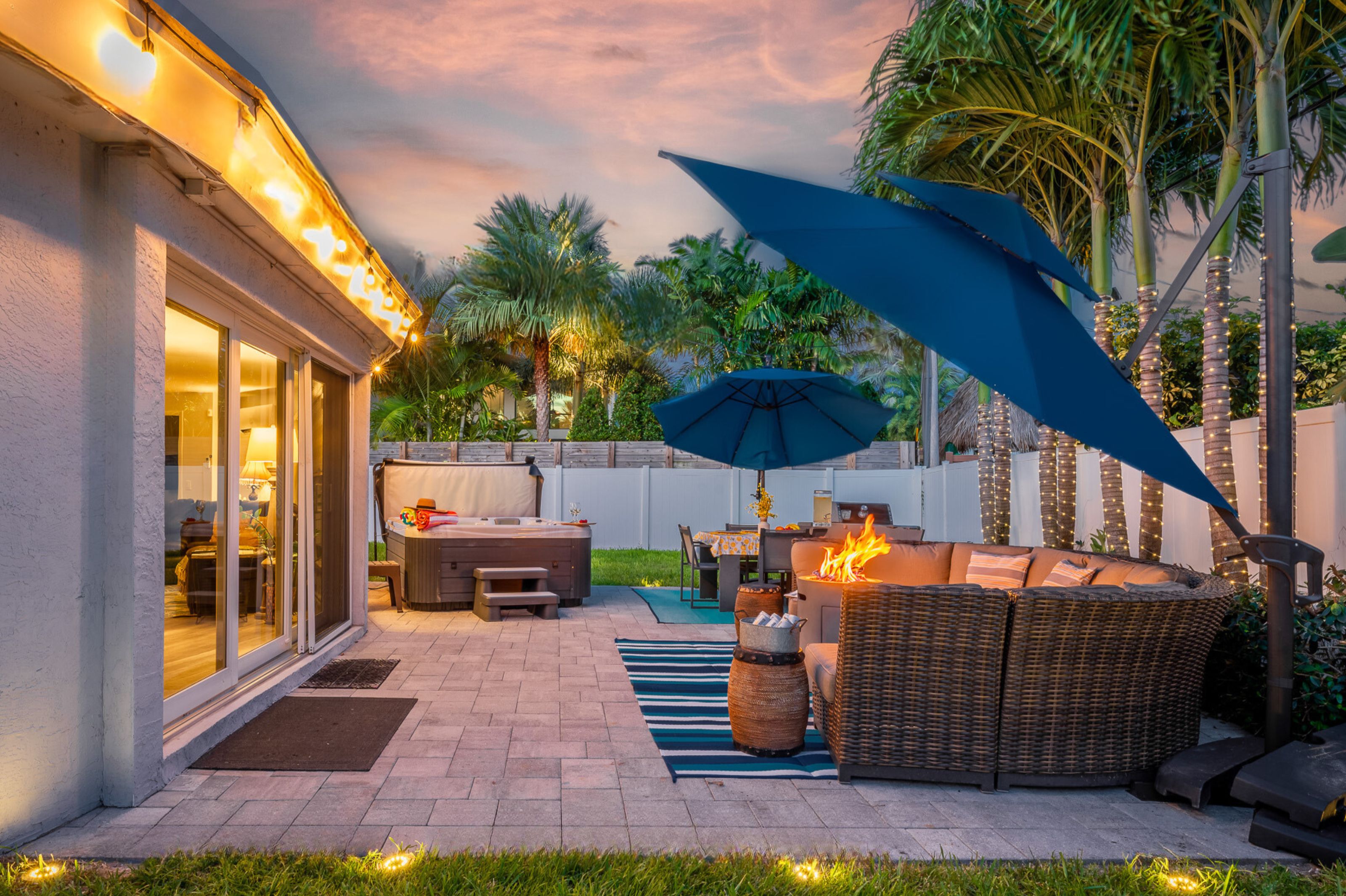 An outdoor patio with a hot tub, seating area, and a covered umbrella.