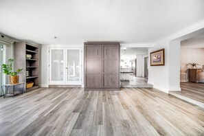 A spacious room with a large sliding door, a wooden cabinet, and a potted plant. - Walk to Beach & Restaurants | Hot Tub | Beach Gear (Pompano Beach)