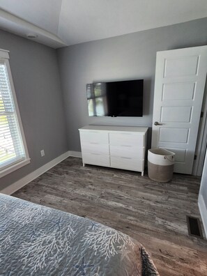 A bedroom with a bed, a dresser, a television, and a door. - Oceanfront Marathon Monthly Rental: Heated Pool + Waterfront + Sunset Views (Marathon)