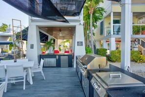 Un espace extérieur aménagé en terrasse, avec un barbecue, des sièges et une vue sur les bâtiments environnants.