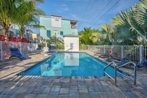 A swimming pool with lounge chairs and a small building in the background. - Oceanfront Marathon Monthly Rental: Heated Pool + Waterfront + Sunset Views (Marathon)