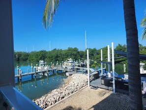 A marina with boats docked, a dock with a covered seating area, and a rocky shoreline. - Oceanfront Marathon Monthly Rental: Heated Pool + Waterfront + Sunset Views (Marathon)