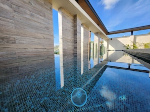 Edifício moderno com área de piscina, apresentando piso de vidro transparente e vista do céu.