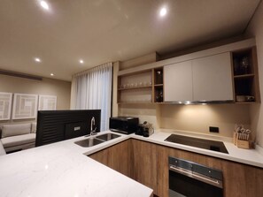 Cozinha moderna equipada com forno embutido, máquina de café e micro-ondas.