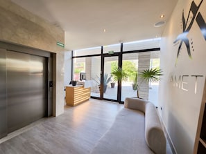 A modern reception area with a reception desk, a seating area, and large windows offering a view of the outdoors. - Ameth: Stylish 3BR in Downtown with Rooftop Pool (Cabo San Lucas)