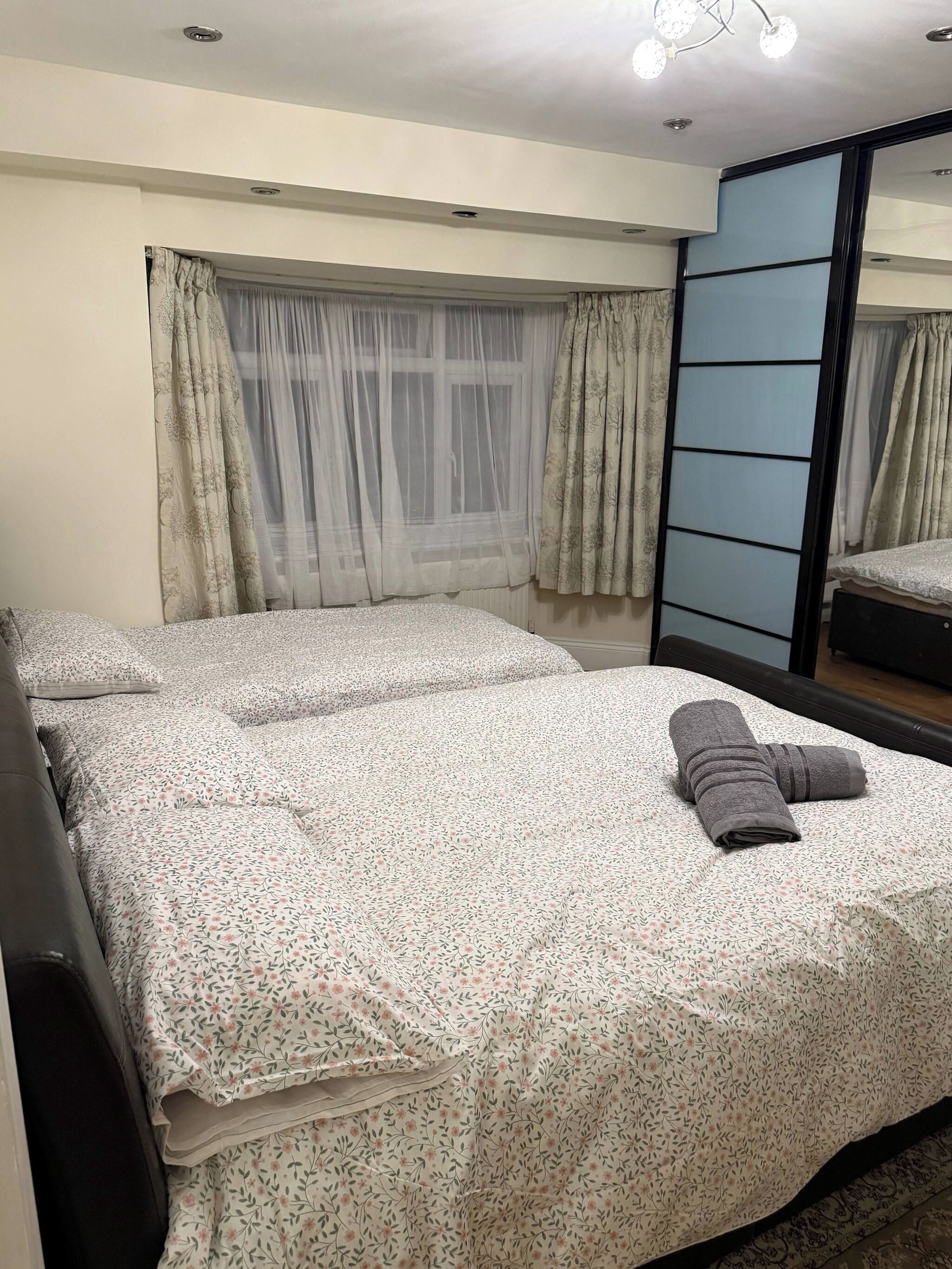 A bedroom with a bed, a mirror, and a window with curtains.