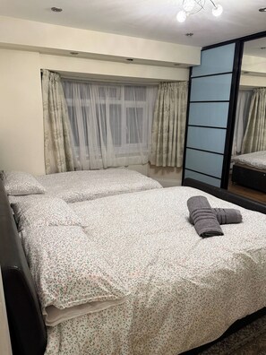 Um quarto com uma cama, um espelho e uma janela com cortinas.