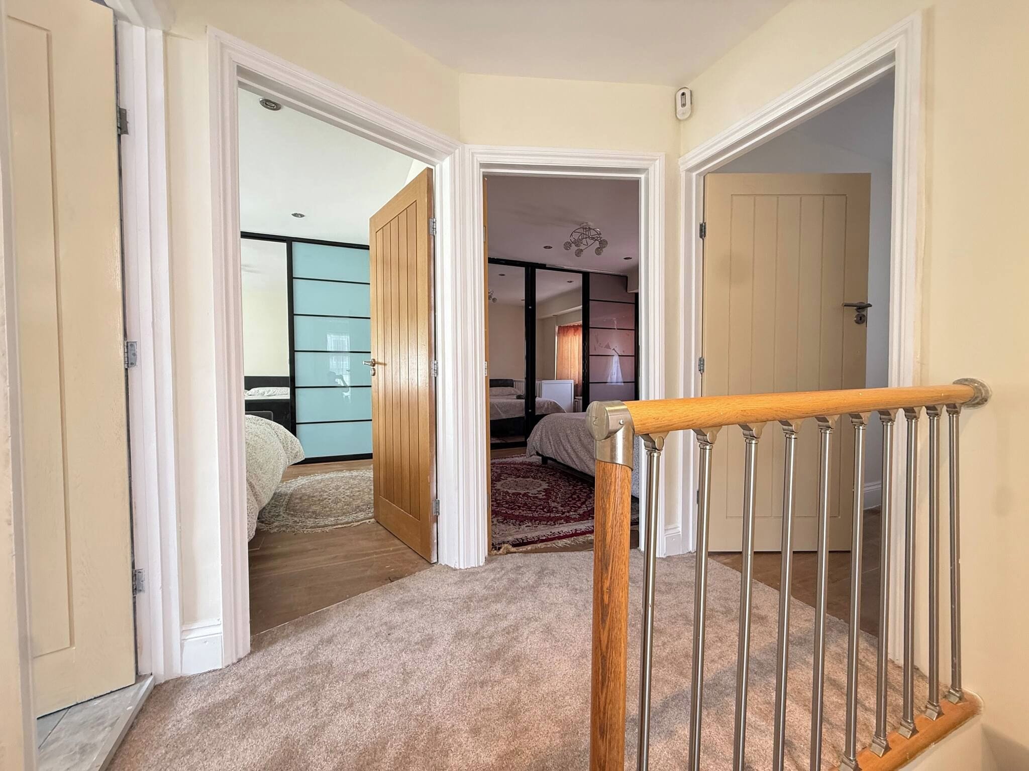 Un couloir dont le sol est recouvert d’une moquette, menant à une chambre à coucher équipée d’un lit et d’une armoire.