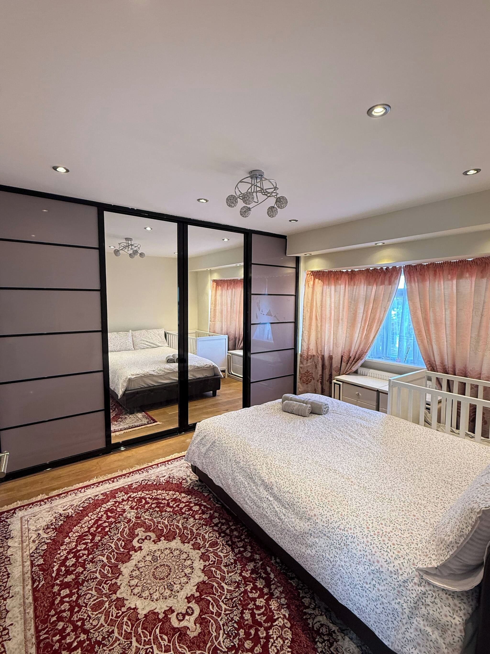 Quarto moderno com cama grande, uma escrivaninha e vista através de uma porta de correr.