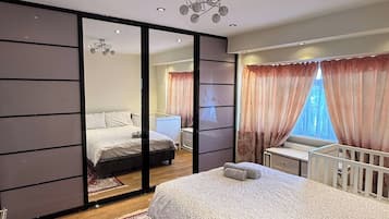 Ein modernes Schlafzimmer mit einem großen Bett, einem Schreibtisch und Blick durch eine Schiebetür.