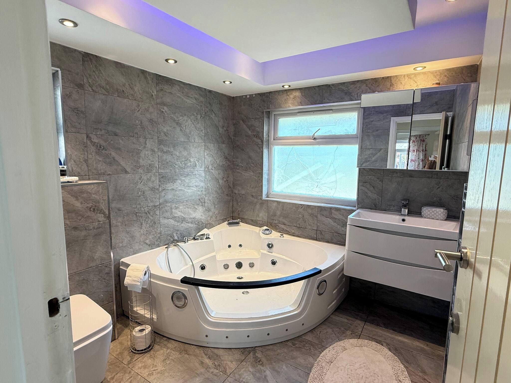 Un baño moderno con una bañera independiente, un tocador con espejo y un ventanal que proporciona luz natural.
